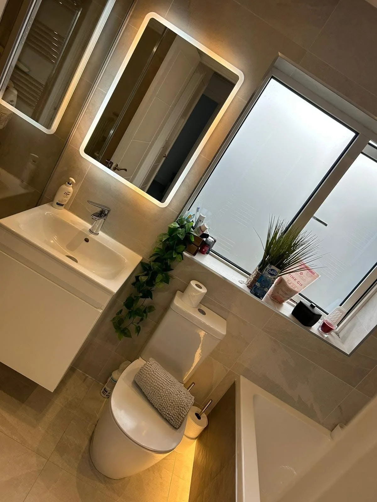 Clean bathroom basin, illuminated mirror and bath