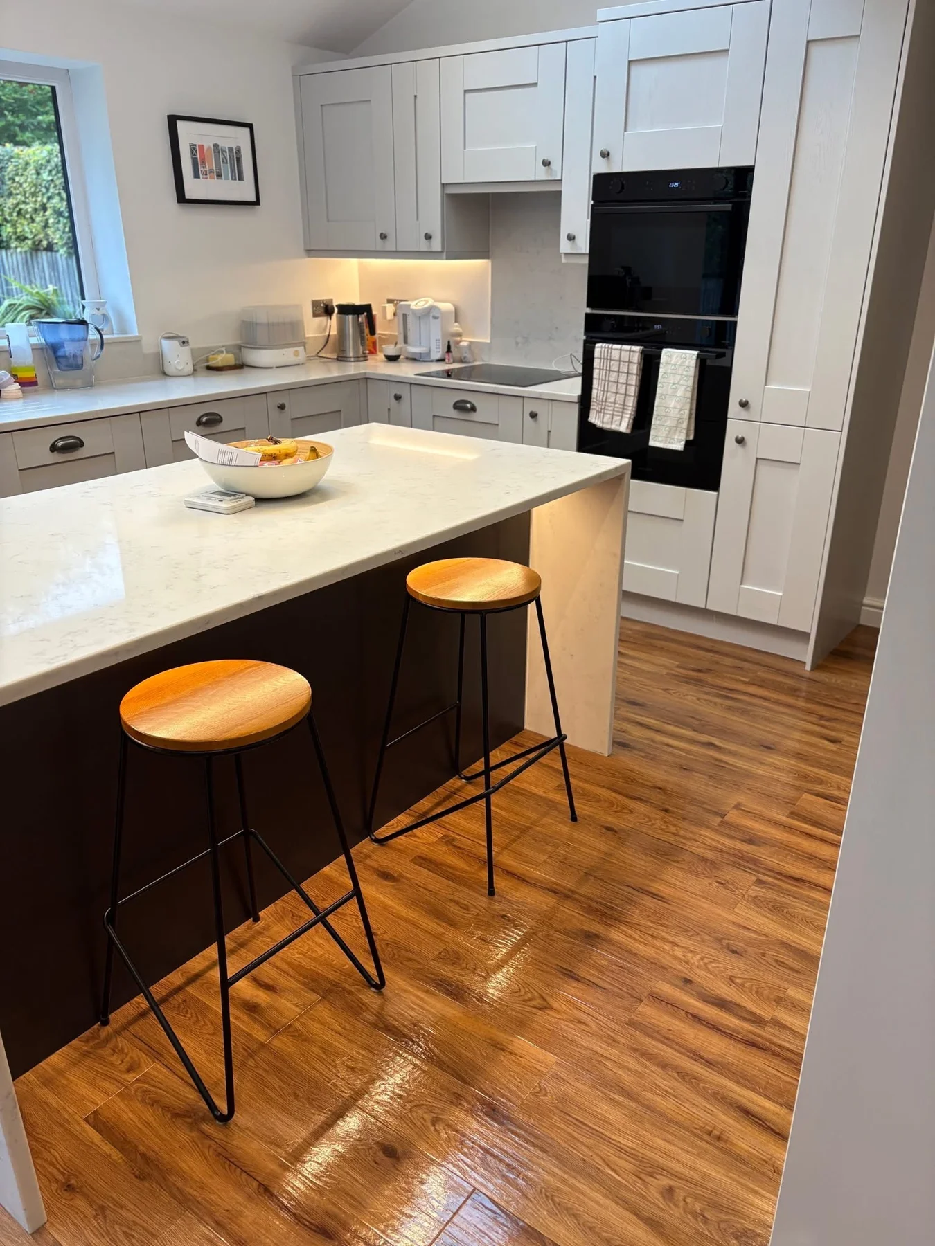 Clean kitchen island, pale cabinets and wood-effect floor