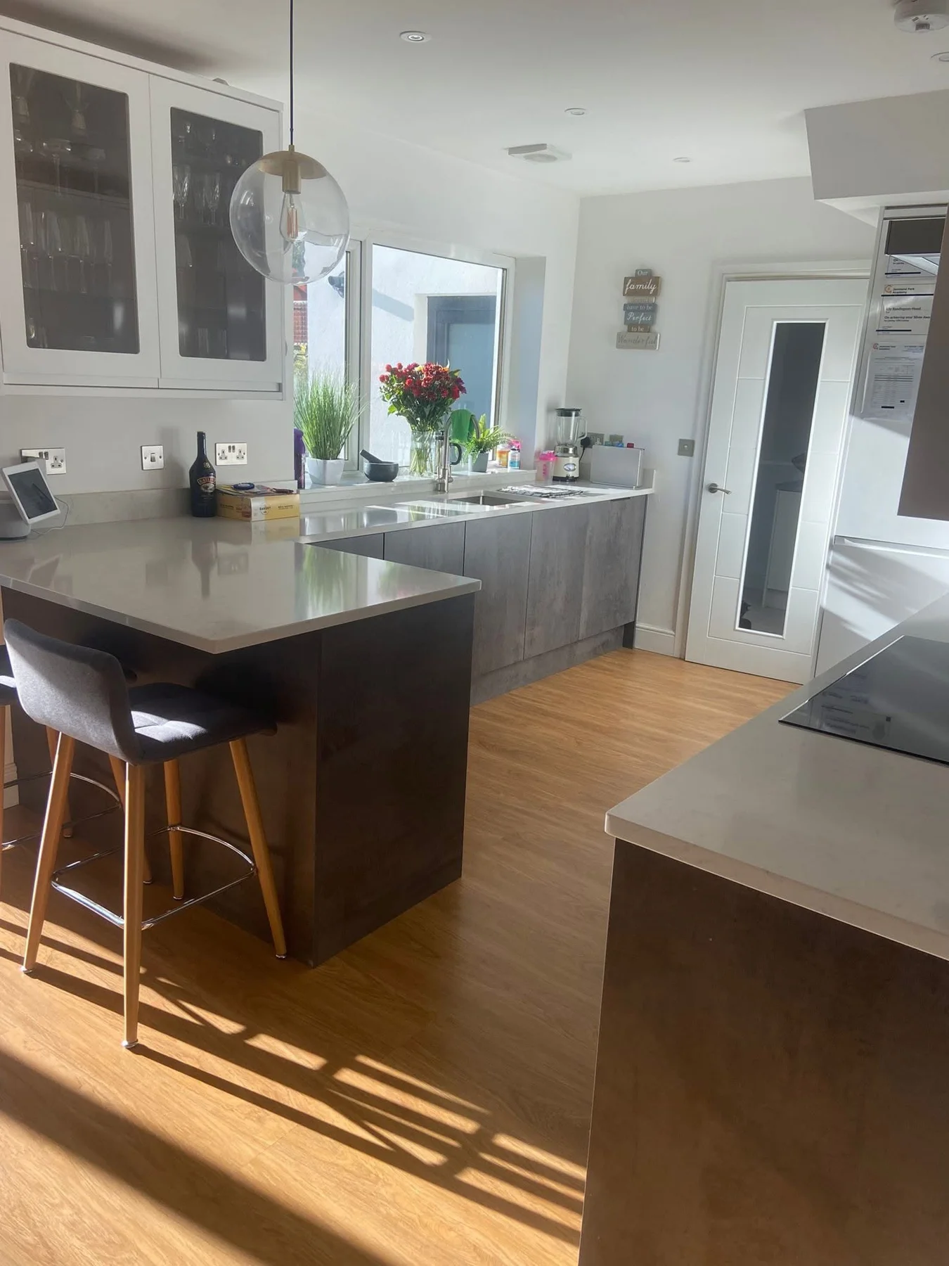 Sunlit kitchen with clean worktops and wood-effect floor